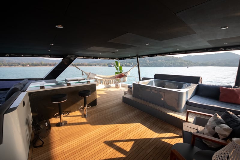 Flybridge with spa pool, bar stools and a hammock under full shade.