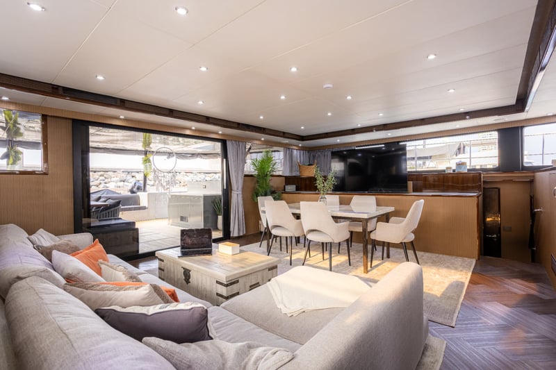 Salon looking aft: sofa, six-seat dining table and wide doors to the cockpit.