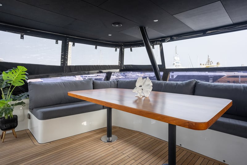 Flybridge dining table with wraparound seating and panoramic glass.