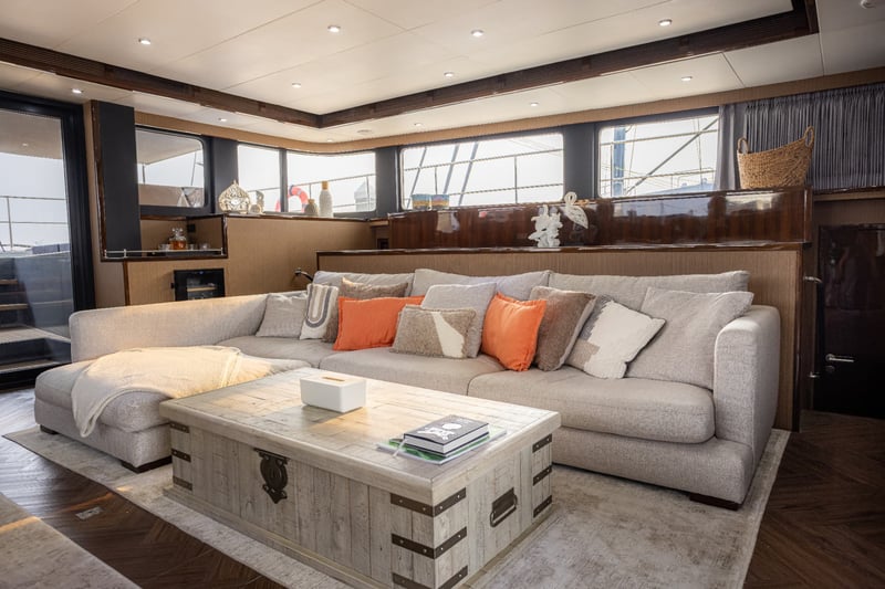 Main salon with a deep sofa, timber chest table and windows all round.